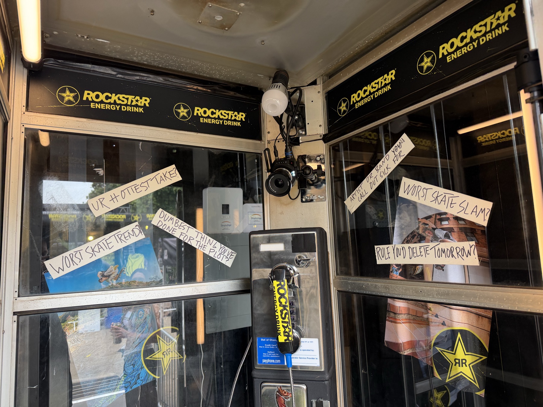 A working payphone surrounded by handwritten prompts inside the Rockstar photo booth.